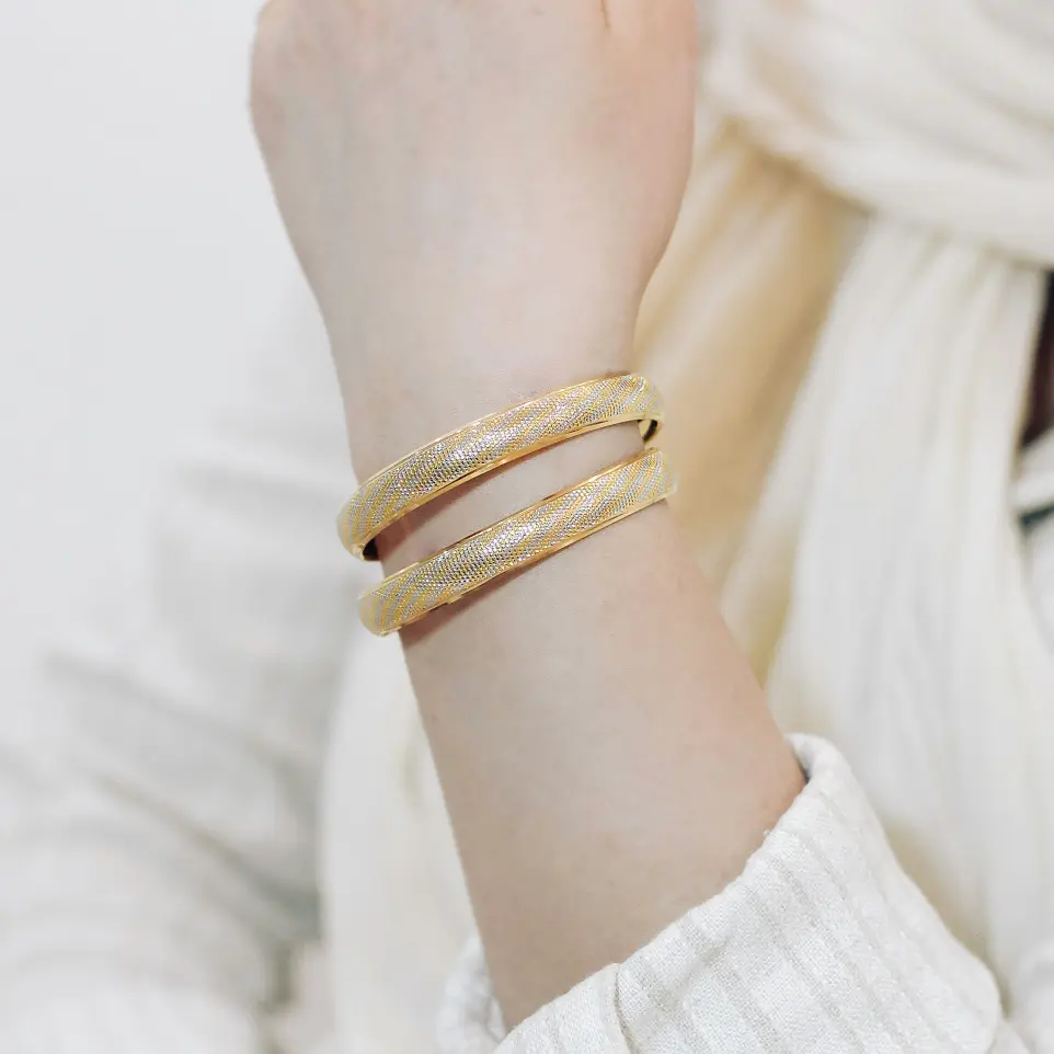 A woman wearing a white sweater and a gold bracelet